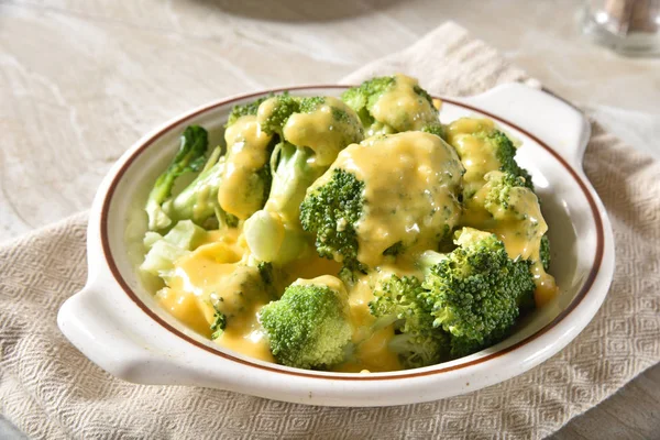Bowl of steamed broccoli with cheddar cheese sauce