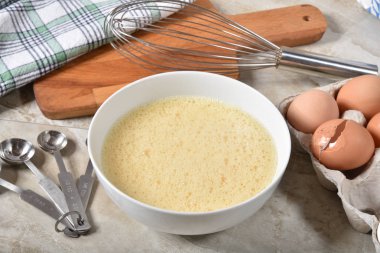 Ölçme kaşık ve bir tel çırpma teli ile dövülmüş kahverengi yumurta bir kase