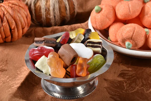 A candy dish of gelatin fruit candies, chocolates, and pumpkin marshmallows in the background for Halloween