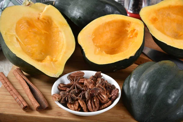 Sliced acorn squash with cinnamon, star anise and pecan halves for holiday cooking.