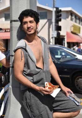 Bir dilim pizza yeme bir sahil kasabası bir lamba sonrası karşı yaslanmış çok etnik gruptan oluşan yakışıklı genç