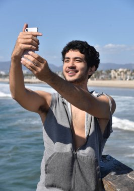 Yakışıklı genç çok etnik gruptan oluşan turistik okyanus üzerinde bir iskelede selfies alarak