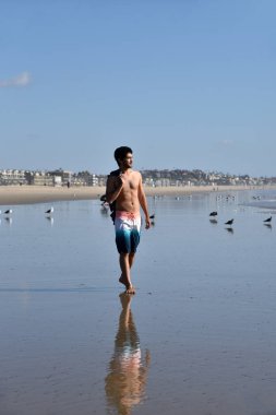 Kaygısız bir genç çok etnik gruptan oluşan adam tropikal bir yerde plajında suların kenarında yürüyüş.