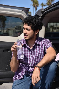 Mutlu bir genç çok etnik gruptan oluşan adam onun Suv Bagaj kapağı su bir şişe ile serinlemek.