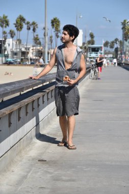 İskelede yürürken bir dilim pizza yemek bir çok etnik gruptan oluşan yakışıklı genç