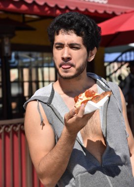 Genç bir adam bir yüz bir dilim biberli pizza yerken çekerek