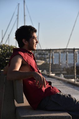 Marina daki teknelerden üzerinden bakan neşeli bir genç adam