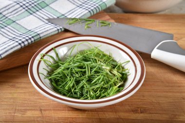 Bir kesme tahtası üzerinde küçük bir kase kıyılmış chives