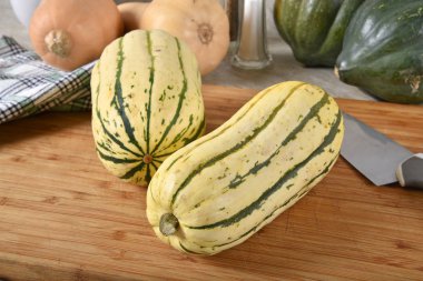 Bir kesme tahtası wth meşe palamudu ve Balkabagi arka planda pişmemiş delicata squash