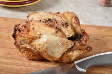 Bir bıçak ile kesme tahtası üzerinde taze pişmiş rotissery tavuk
