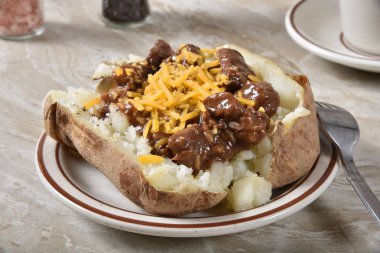 Sığır eti ipuçları ve et suyu ile kaşar peyniri ile tepesinde bir fırında patates