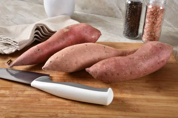 Vers Ongekookt Zoete Aardappelen Een Snijplank Met Een Keukenmes — Stockfoto