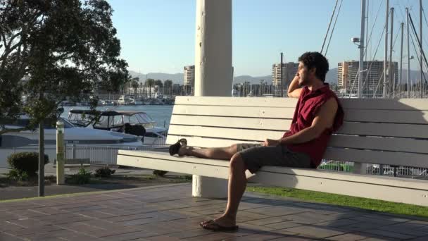Jovem Bonito Relaxando Banco Por Uma Marina Veleiro — Vídeo de Stock