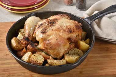 Pişmiş bebek patates tarafından çevrili bir dökme demir tavada kavrulmuş tavuk