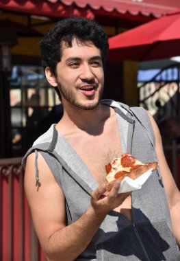 Serin çok etnik gruptan oluşan genç adam bir dilim pizza açık havada şirin bir kasabada yemek