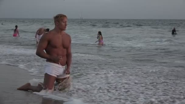 肌肉健美运动员跪在海浪在海洋 — 图库视频影像