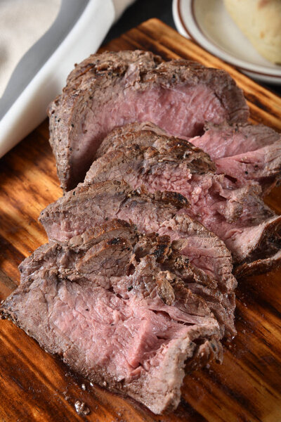 Sirloin roast beef sliced thin on a wooden cutting board