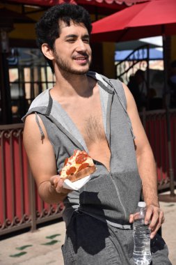 Eğlenceli sevgi dolu genç adam yemek pizza açık havada