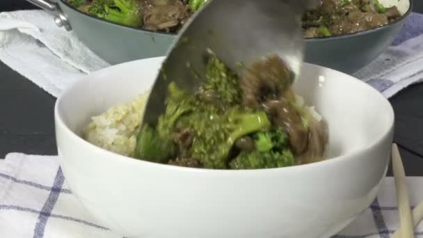 Serverar Hemlagad Nötkött Och Broccoli Över Skål Med Ångad Ris — Stockvideo