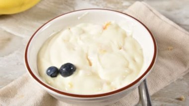 Dilimlenmiş muz ve granola ile tepesinde olan yoğurt bir kase hareket animasyon durdurun