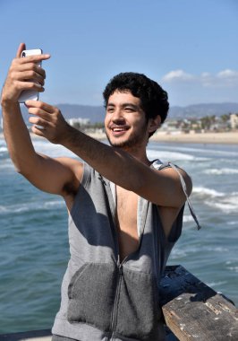 Mutlu genç erkek turist okyanus iskelesi üzerinde selfie çekerken