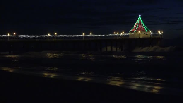 海の桟橋を飾るクリスマスライトに反射する波 — ストック動画