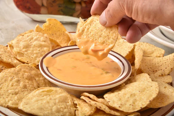Dipping a tortilla chip in cheese sauce — Stock Photo, Image