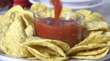 Tortilla cipsli bir tabağa salsa sosu dök, ağır çekimde.