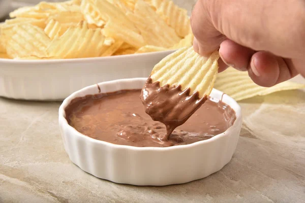 Dipping a potato chip into melted chocolate — Stock Photo, Image