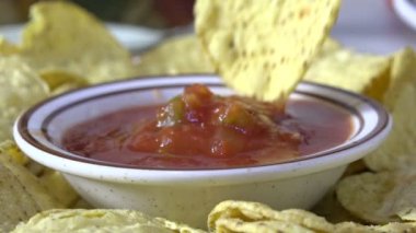 Mısır cipsini bir kase salsa sosuna bandırıyorum.
