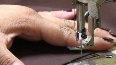 Profesyonel terzi kilidi. Kahverengi bir elbiseye dikiş atıyor.