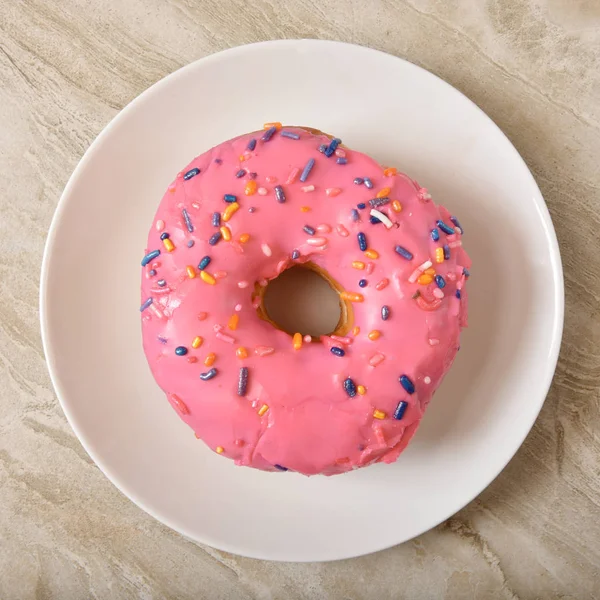 Donut com cobertura rosa e polvilhas de doces — Fotografia de Stock