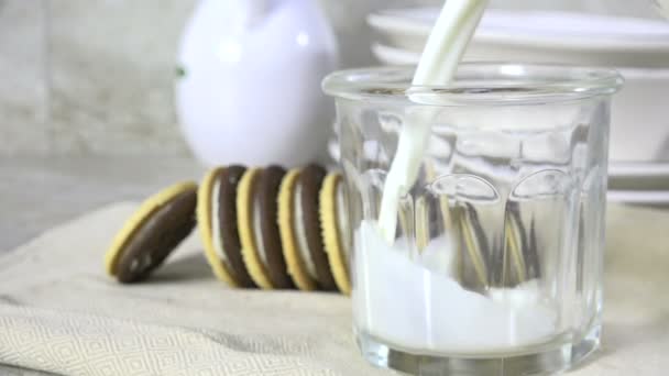 ミルクをクリーム入りサンドイッチクッキーの隣のガラスに入れる — ストック動画