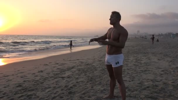Ένα Αρσενικό Bodybuilder Απολαμβάνοντας Την Παραλία Στο Ηλιοβασίλεμα — Αρχείο Βίντεο