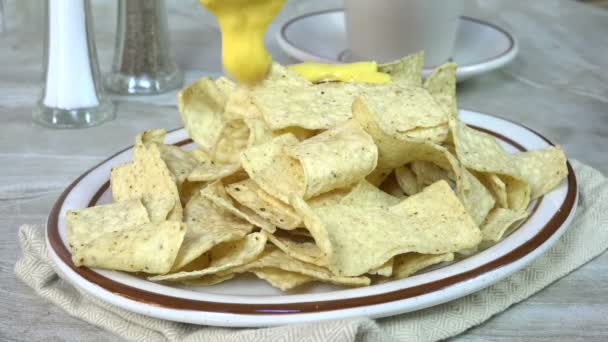 Heiße Käsesauce Auf Einen Teller Mit Mais Tortilla Chips Gießen — Stockvideo