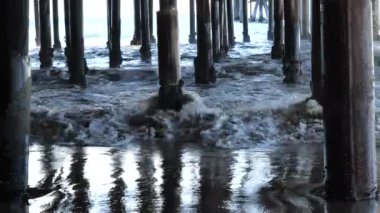 Okyanus dalgaları bir iskelenin altında kıyıya vuruyor. 