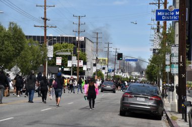 Beverly Hills, CA / USA - 30 Mayıs 2020: Fairfax İlçesi 'ndeki Üçüncü Cadde' de daha fazla Siyahi Yaşamı Değerli protestocu yürürken, yanan polis arabalarından yükselen duman üzerine polis helikopteri uçakları