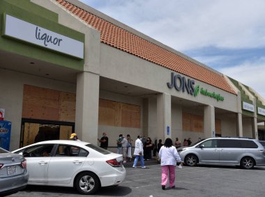 Los Angeles, CA - 1 Haziran 2020: Yüzü maskeli müşteriler, daha fazla Siyahi Yaşamı Önemi Protestosu beklentisiyle şehirde tahta döşeyen bir markete girmek için bekliyorlar