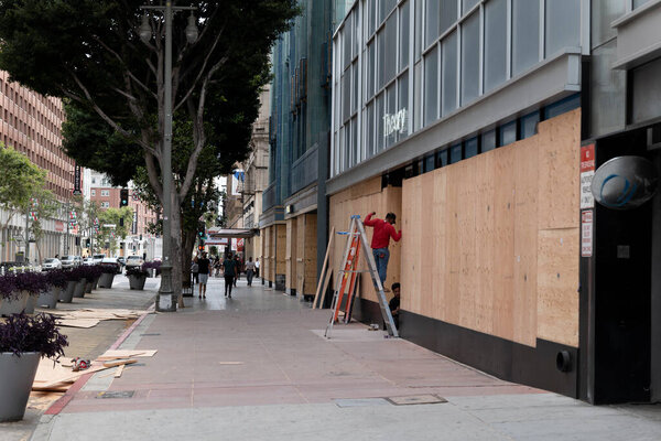 Los Angeles, CA / USA - June 1, 2020: Workers boarding up businesses near the historic Eastern Columbia Building in downtown LA after Black Lives Matter riots on May 29th
