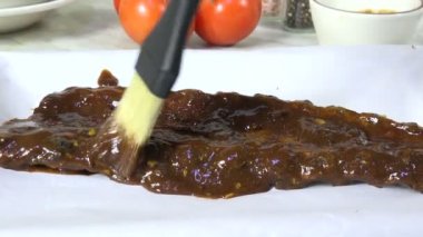 Brushing barbecue sauce on beef ribs