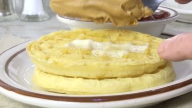 Spreading peanut butter on a waffle slow motion