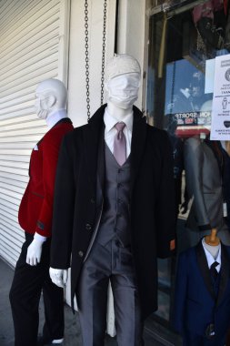 Los Angeles, CA - May 19, 2020: A Mens fashion store in the Los Angeles Fashion District dresses store mannequins with face masks after coronavirus quarantine