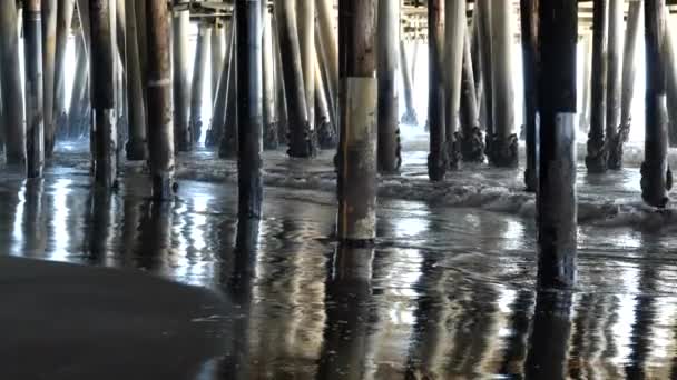 太平洋の大きな桟橋の下で海岸に転がり込む波 — ストック動画