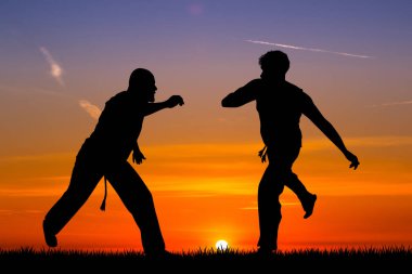 Erkekler capoeira günbatımında dans.