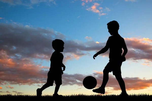 children play soccer at sunset