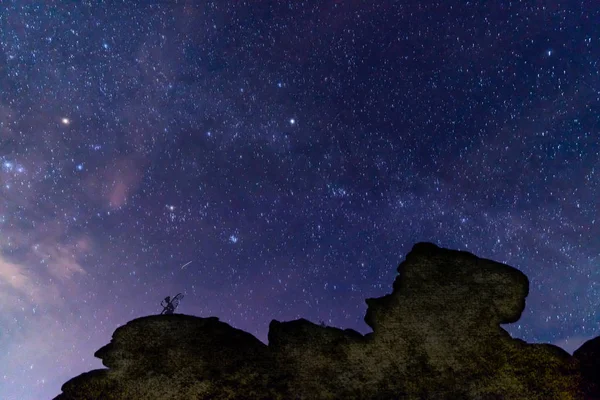 Fairy under the stars.  A fairy sitting on a rock outcrop with the night sky above.