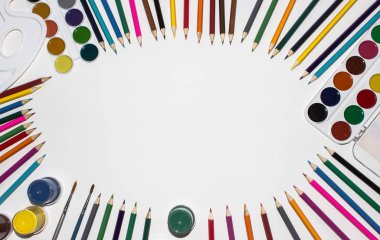 Renkli kalemler, boyalar ve beyaz arka planda fırçalar. Üstten görünüm, kopya alanı.