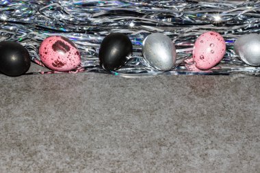 Paskalya yumurtaları. Pembe, gümüş ve siyah renkli parlak tinsel gri bir arka plan üzerinde yumurta. Paskalya duvar kağıdı. Kopya alanı.