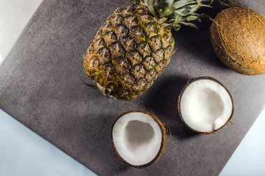 Olgun ananas ve hindistan cevizi koyu bir arka plan, üst görünümü. Sağlıklı gıda ve yaşam tarzı kavramı.