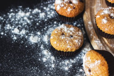 Siyah bir arka plan üzerinde şeker tozu ile ev yapımı cupcakes. Seçici odaklama, üst görünüm, kopyalama alanı.